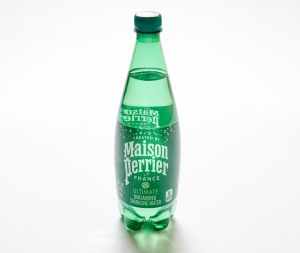 A green plastic bottle of Crystal Geyser Sparkling water with a green cap stands on a white surface.