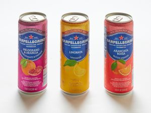 Three San Pellegrino sodas, assorted flavors, are arranged upright on a white surface.