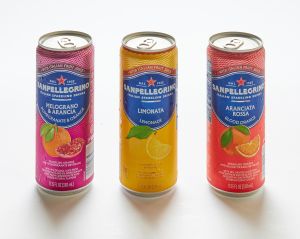 Three San Pellegrino sodas, assorted flavors, are arranged upright on a white surface.
