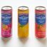 Three San Pellegrino sodas, assorted flavors, are arranged upright on a white surface.
