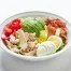 A white bowl holds a Cobb salad with chicken, bacon, avocado, blue cheese, tomatoes, eggs, and Ranch dressing in San Francisco on a white background.