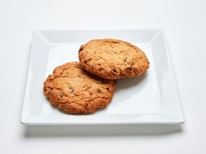 Two Coconut Cranberry Cookies on a white square plate.