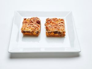 Two 7-Layer Bars topped with white drizzle on a square white plate.