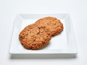 Two Oatmeal Raisin Cookies on a square white plate against a plain background.