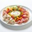 A white plate with assorted cured meats, cheeses, and colorful peppers arranged around a bowl of creamy dip in the center—perfect for sharing at parties or adding to your favorite platters.
