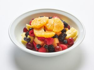 A white bowl filled with assorted fresh fruit, including orange slices, grapes, blackberries, raspberries, blueberries, cantaloupe, honeydew, and pineapple—perfect for colorful platters or healthy gatherings.